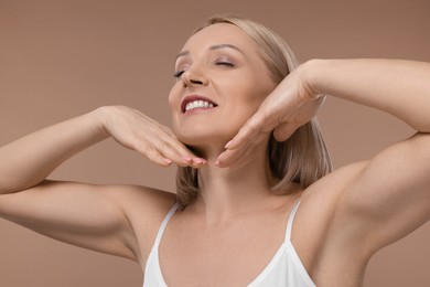 Beautiful woman touching her neck on beige background