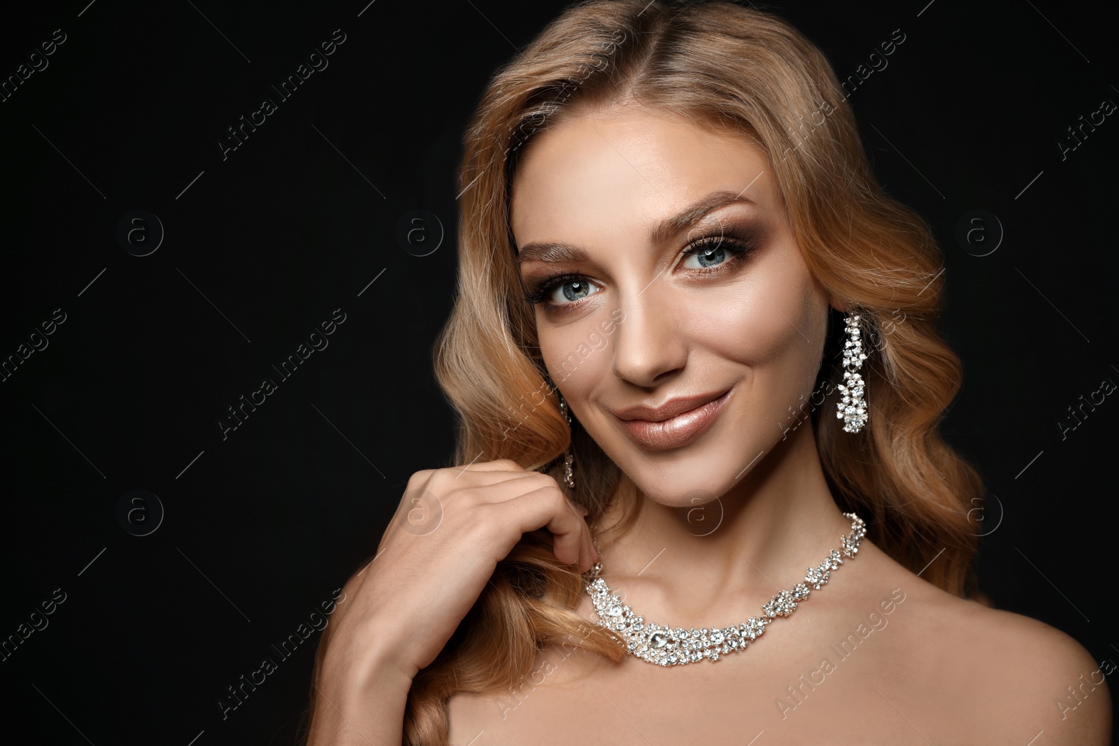 Photo of Beautiful young woman with elegant jewelry on dark background. Space for text