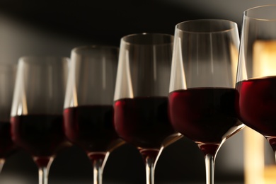Photo of Glasses of red wine against blurred background, closeup. Expensive drink