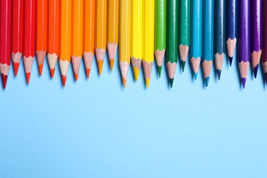Photo of Colorful pencils on light blue background, flat lay. Space for text