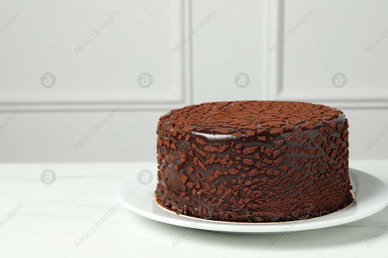 Photo of Delicious chocolate truffle cake on white marble table, space for text