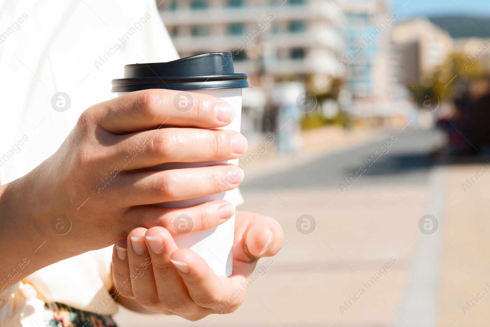 Photo of Woman holding takeaway coffee cup outdoors, closeup. Space for text