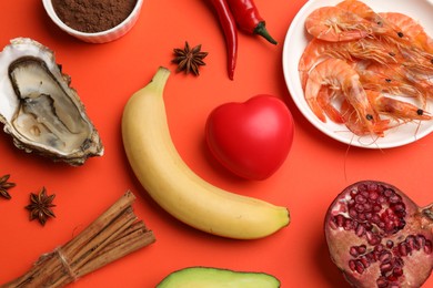 Photo of Natural aphrodisiac. Different food products and red decorative heart on orange background, flat lay