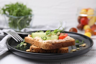 Tasty vegan sandwich with cucumber, tomato and pumpkin seeds on white wooden table, closeup