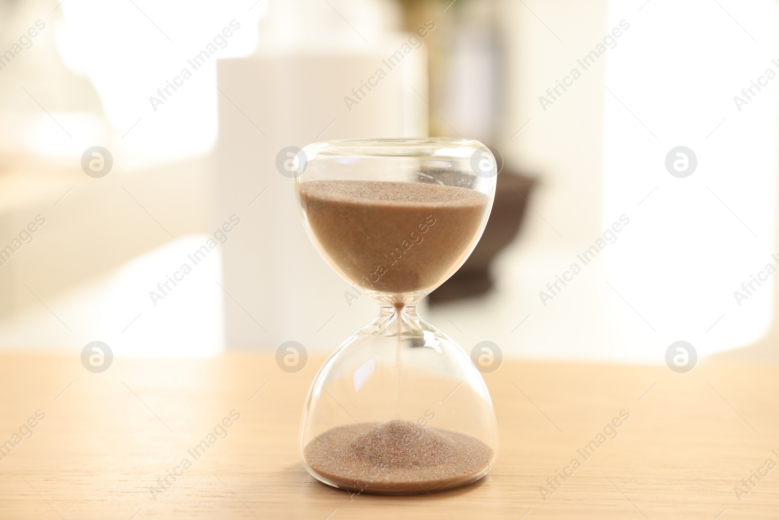 Photo of Sandglass on wooden table indoors, closeup. Spa time