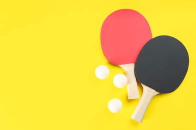 Photo of Ping pong rackets and balls on yellow background, flat lay. Space for text
