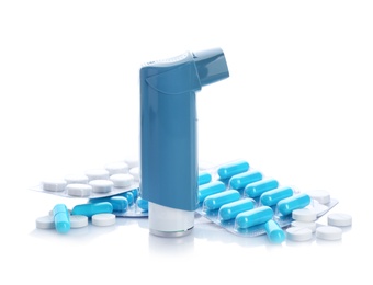 Asthma inhaler and pills on white background