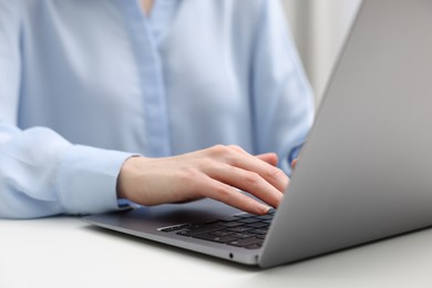 E-learning. Woman using laptop at white table indoors, closeup