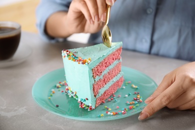 Photo of Woman eating fresh delicious birthday cake at table, closeup