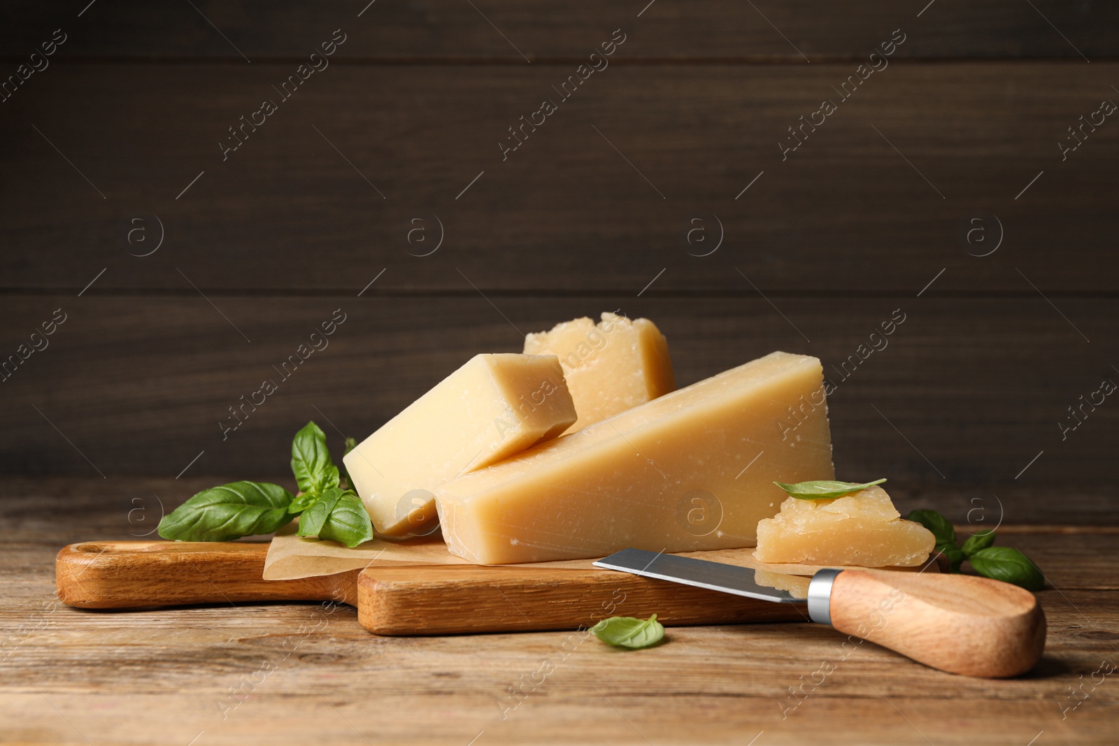 Photo of Delicious parmesan cheese with basil and knife on wooden table
