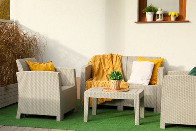 Photo of Beautiful rattan garden furniture, soft pillows, blanket and houseplant outdoors