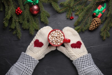 Photo of Woman with cup of delicious hot cocoa at black table, top view