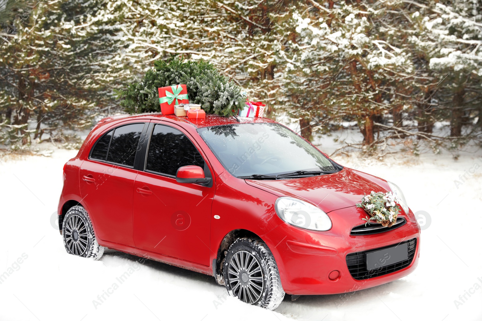 Photo of Car with Christmas tree, wreath and gifts in snowy forest on winter day