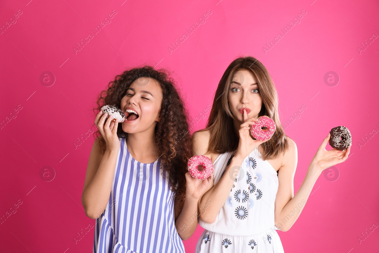 Photo of Beautiful young women with donuts on pink background