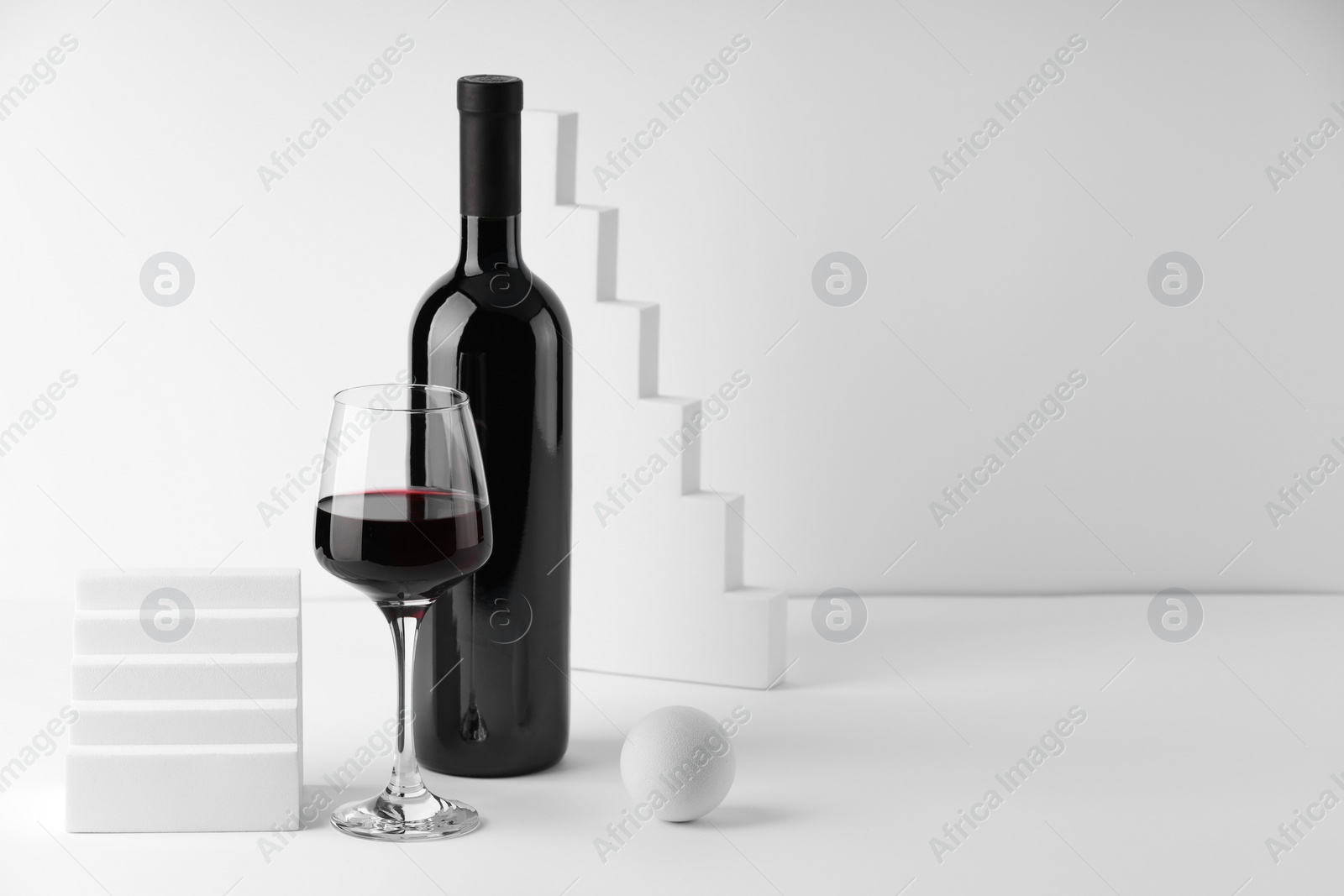 Photo of Stylish presentation of delicious red wine in bottle and glass on white background. Space for text