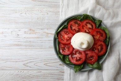 Photo of Delicious burrata cheese with tomatoes and basil on white wooden table, top view. Space for text