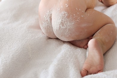 Photo of Little baby covered with dusting powder on towel, closeup. Space for text