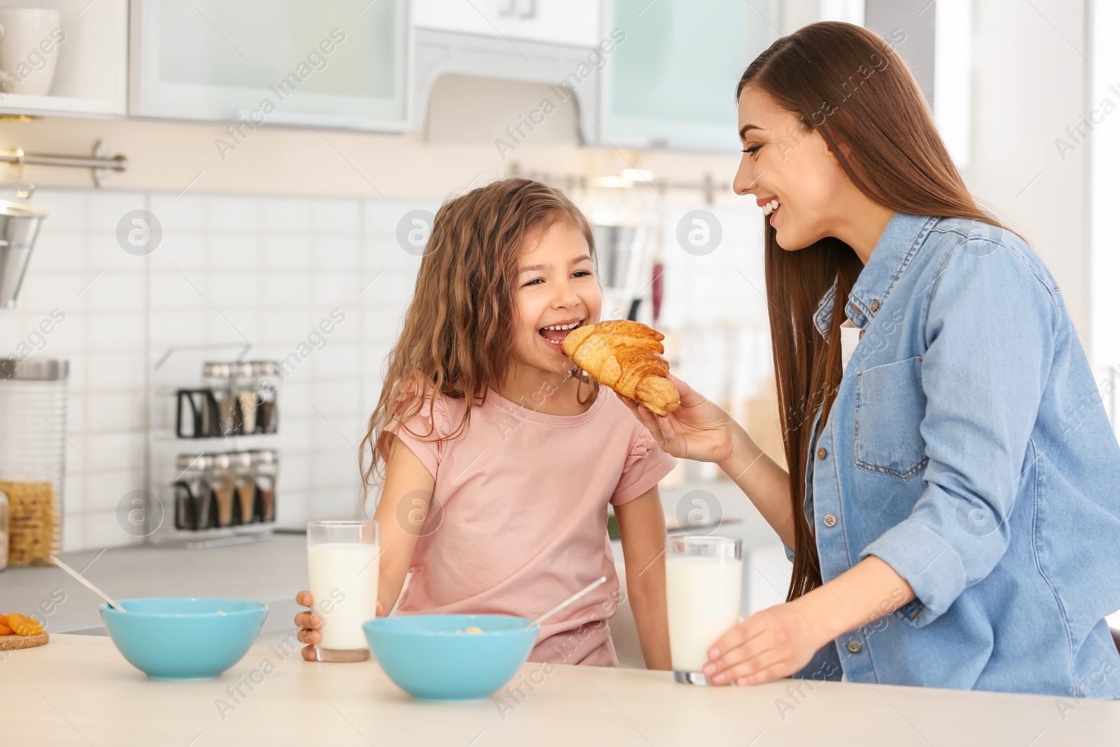 Photo of Mother and daughter having breakfast with milk at table