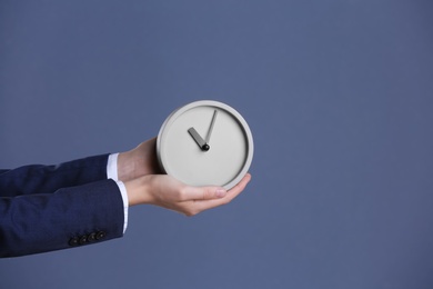 Photo of Businesswoman holding alarm clock on color background. Time concept