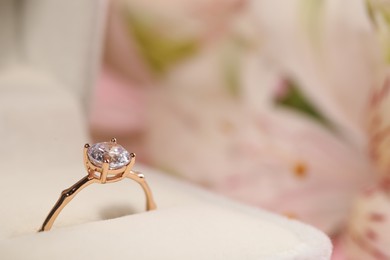 Photo of Beautiful engagement ring with gemstone in box on blurred background, closeup. Space for text