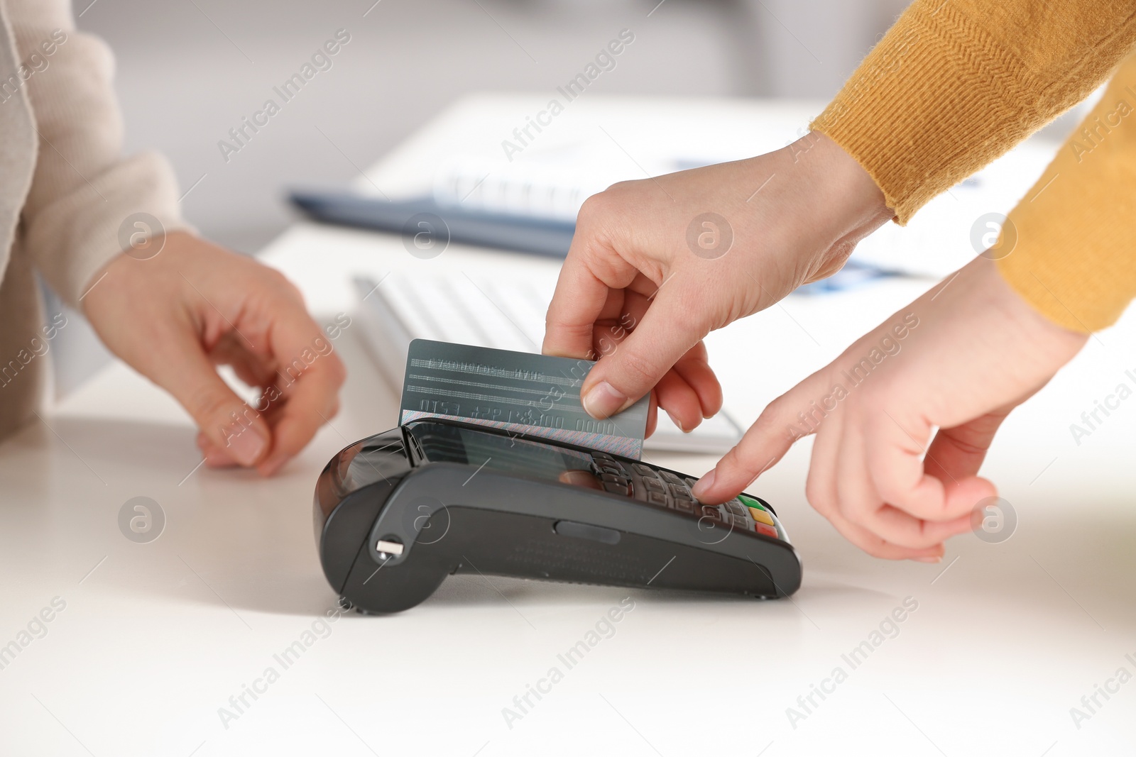 Photo of Women using modern payment terminal at table indoors, closeup