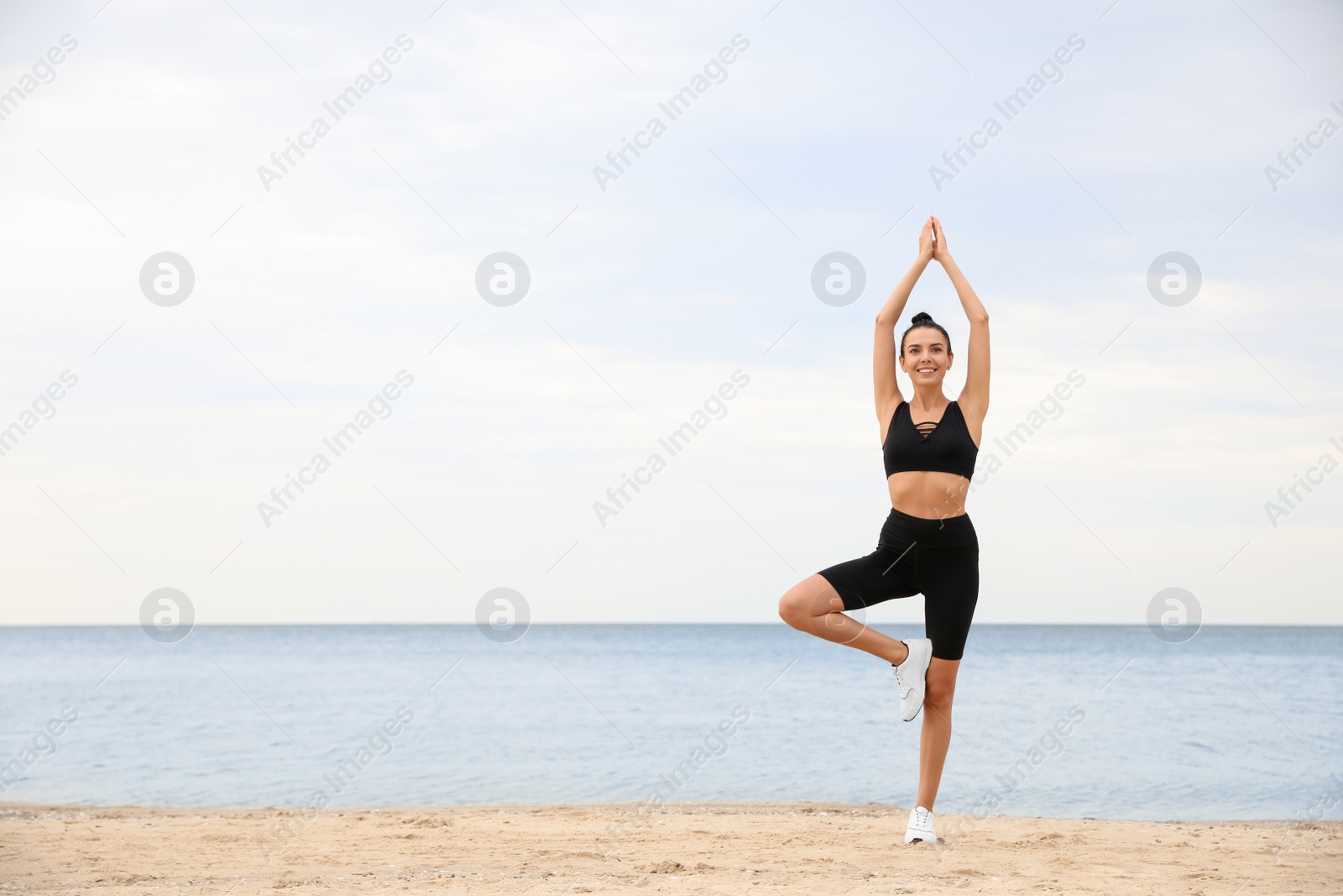 Photo of Young woman doing exercise on beach, space for text. Body training