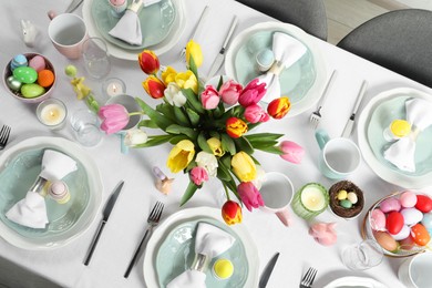 Festive Easter table setting with beautiful flowers and painted eggs, top view