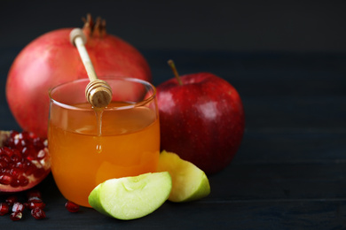 Photo of Honey, apples and pomegranate on dark wooden table, closeup. Rosh Hashanah holiday