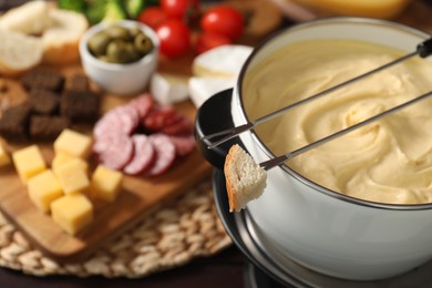 Photo of Fondue with tasty melted cheese, forks and piece of bread on table, closeup. Space for text