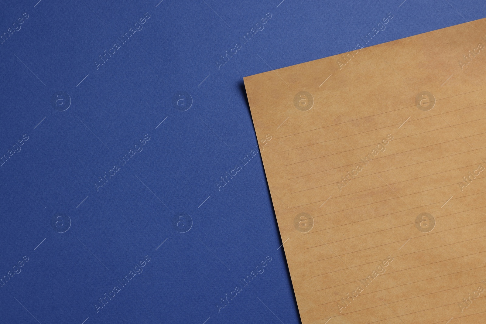 Photo of Sheet of old parchment paper on blue background, top view. Space for text