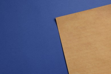 Photo of Sheet of old parchment paper on blue background, top view. Space for text