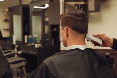 Photo of Professional hairdresser making stylish haircut in salon, back view