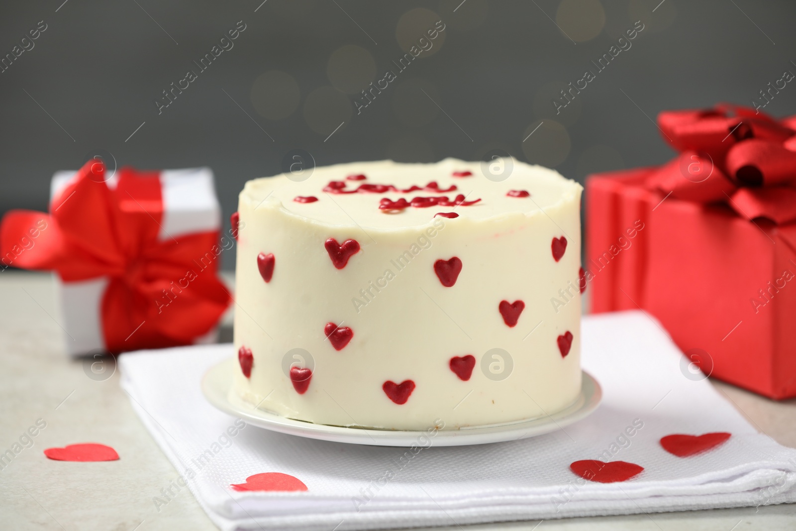 Photo of Bento cake with red cream hearts and gift boxes on grey table. St. Valentine's day surprise