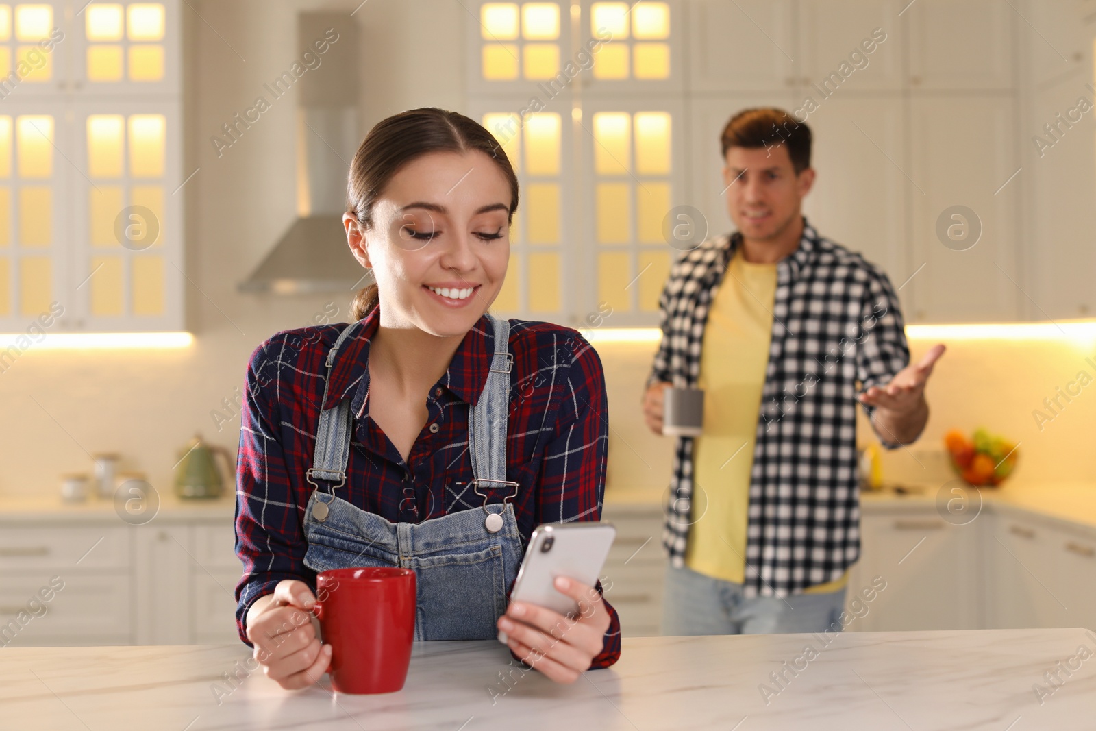 Photo of Woman preferring smartphone over spending time with her boyfriend at home. Jealousy in relationship