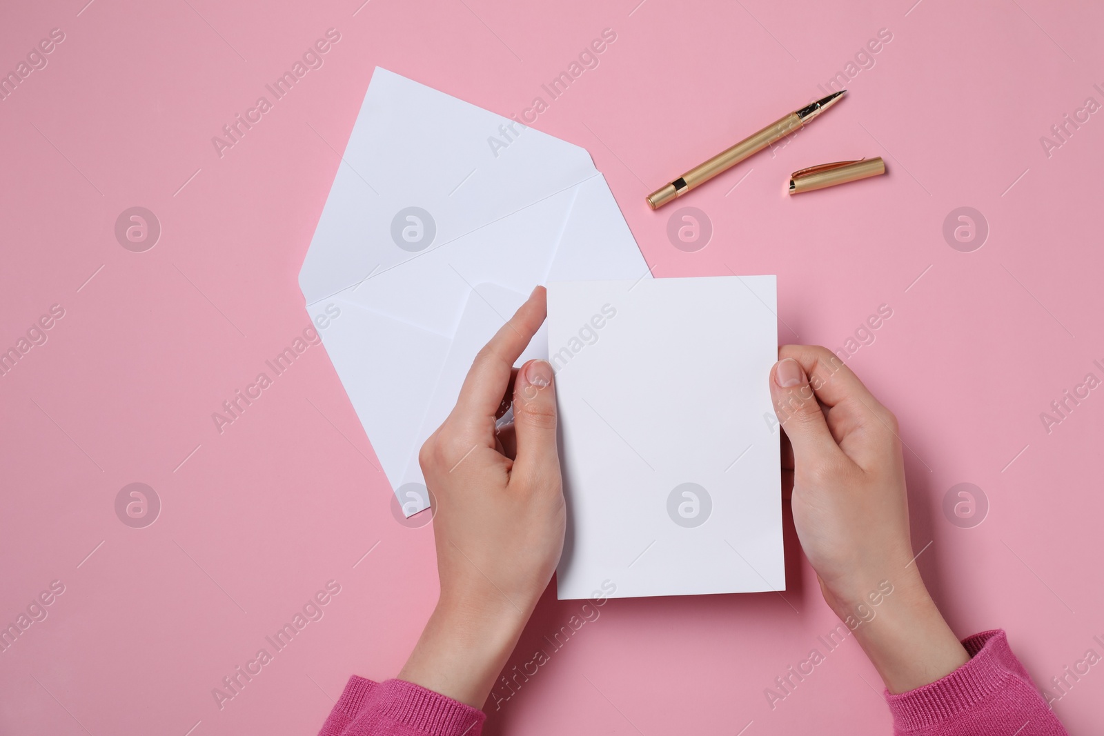 Photo of Woman with blank card at pink table, top view. Space for text