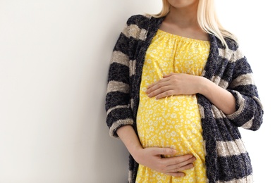 Pregnant woman on light background, closeup. Space for text