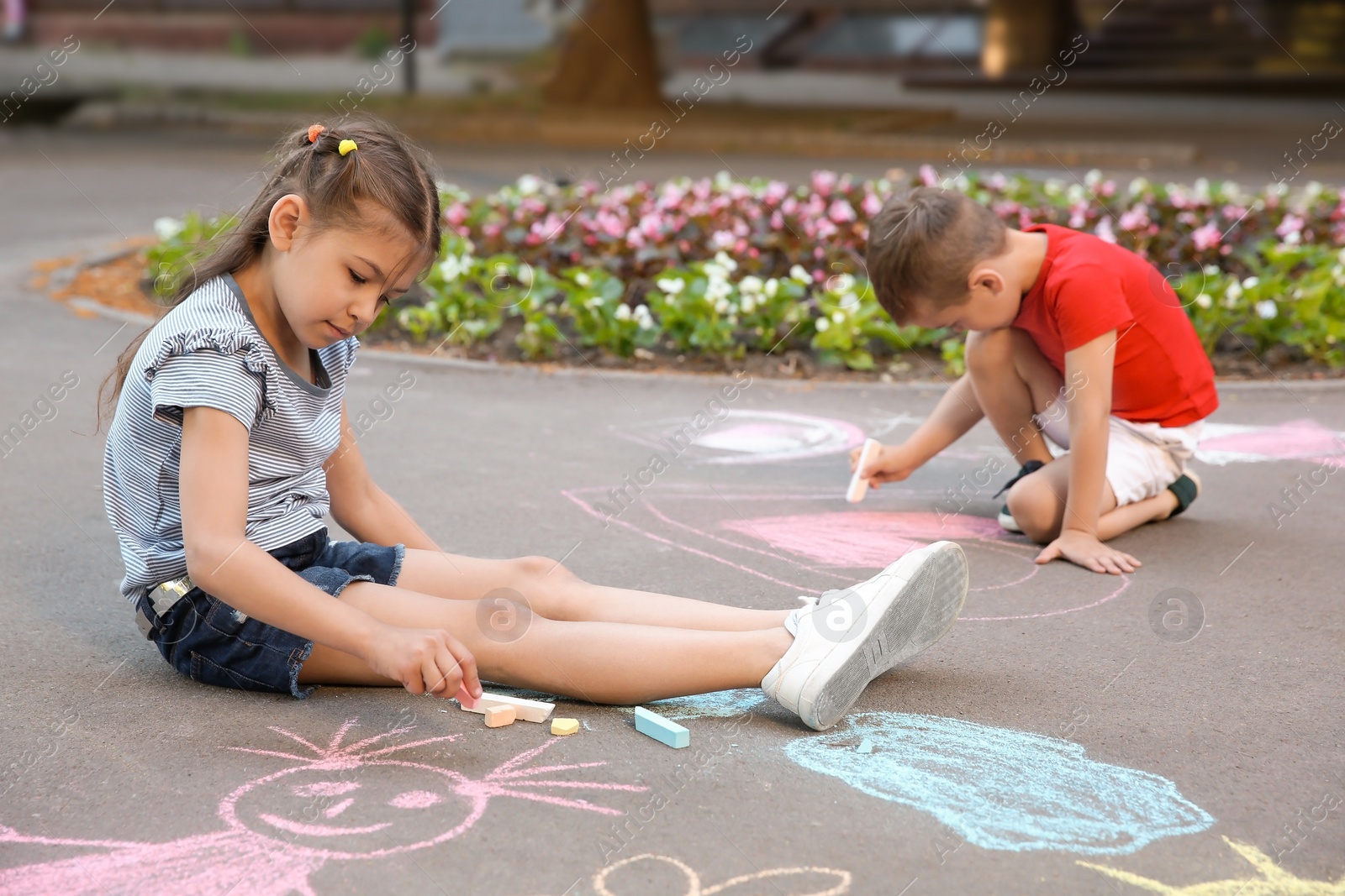 Photo of Little children drawing with colorful chalk on asphalt