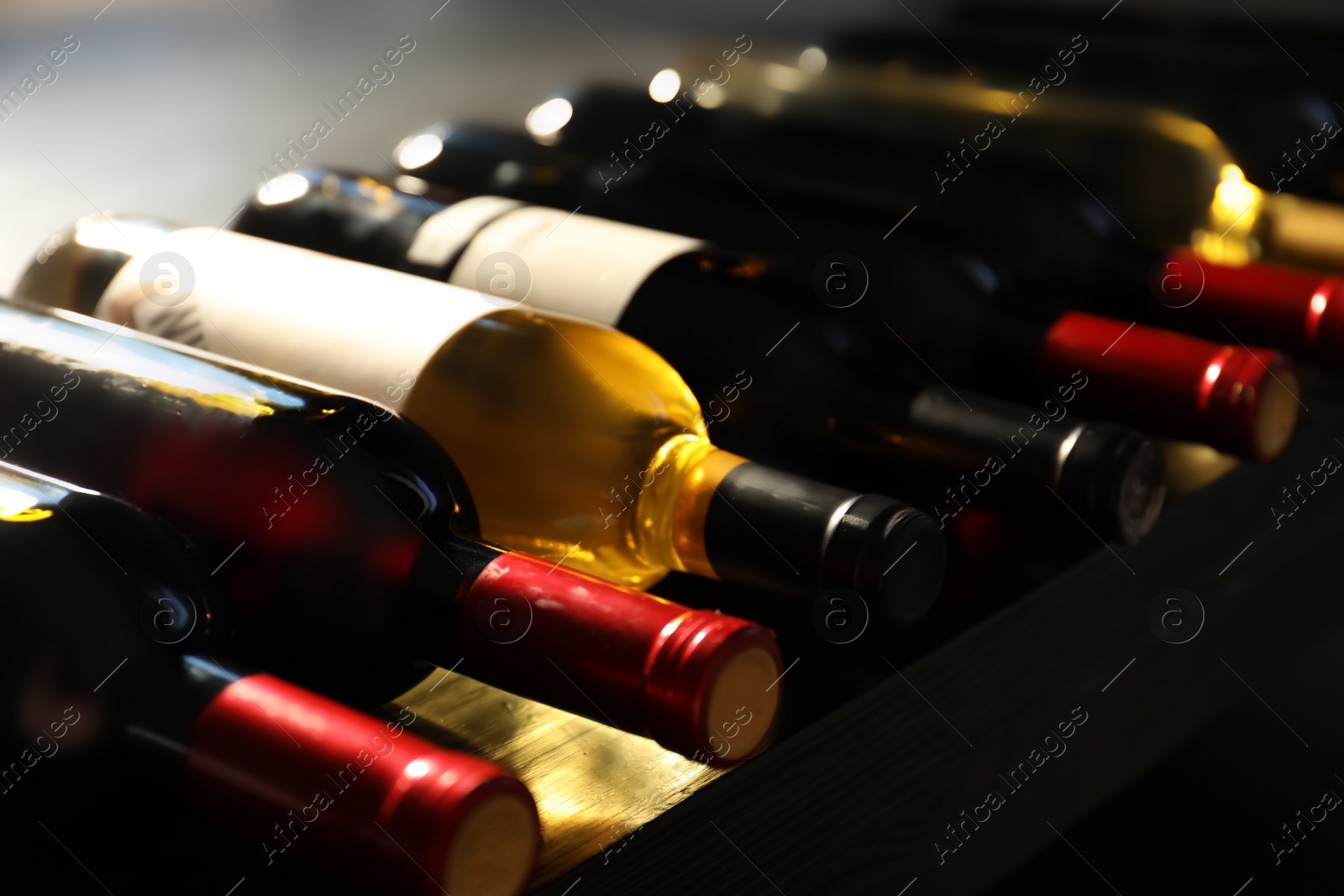 Photo of Bottles with delicious wine on shelf, closeup. Professional sommelier