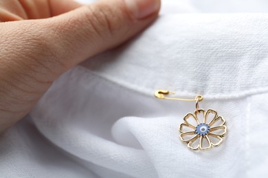 Photo of Woman holding clothing with evil eye safety pin, closeup