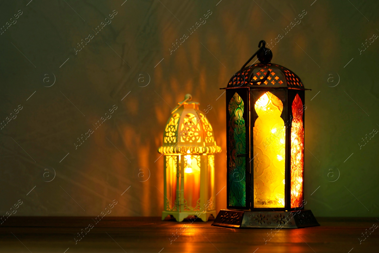 Photo of Decorative Arabic lanterns on table against dark background. Space for text