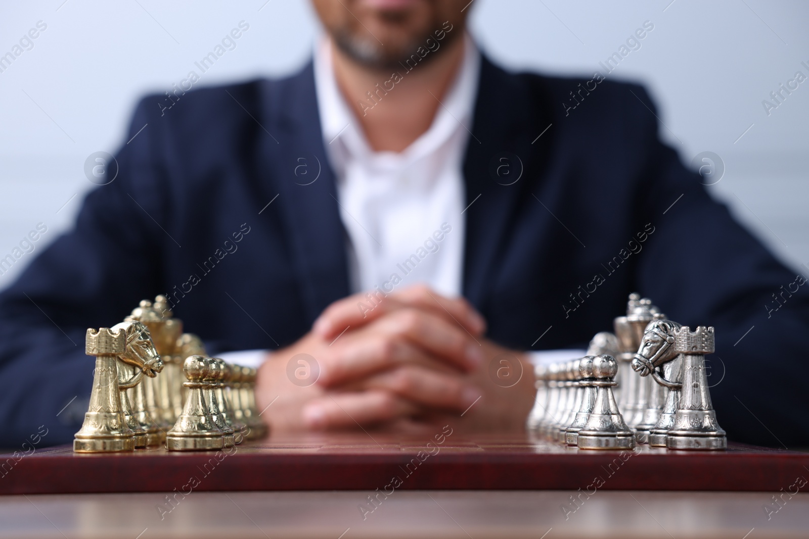 Photo of Man with chess pieces on checkerboard at table before game, closeup