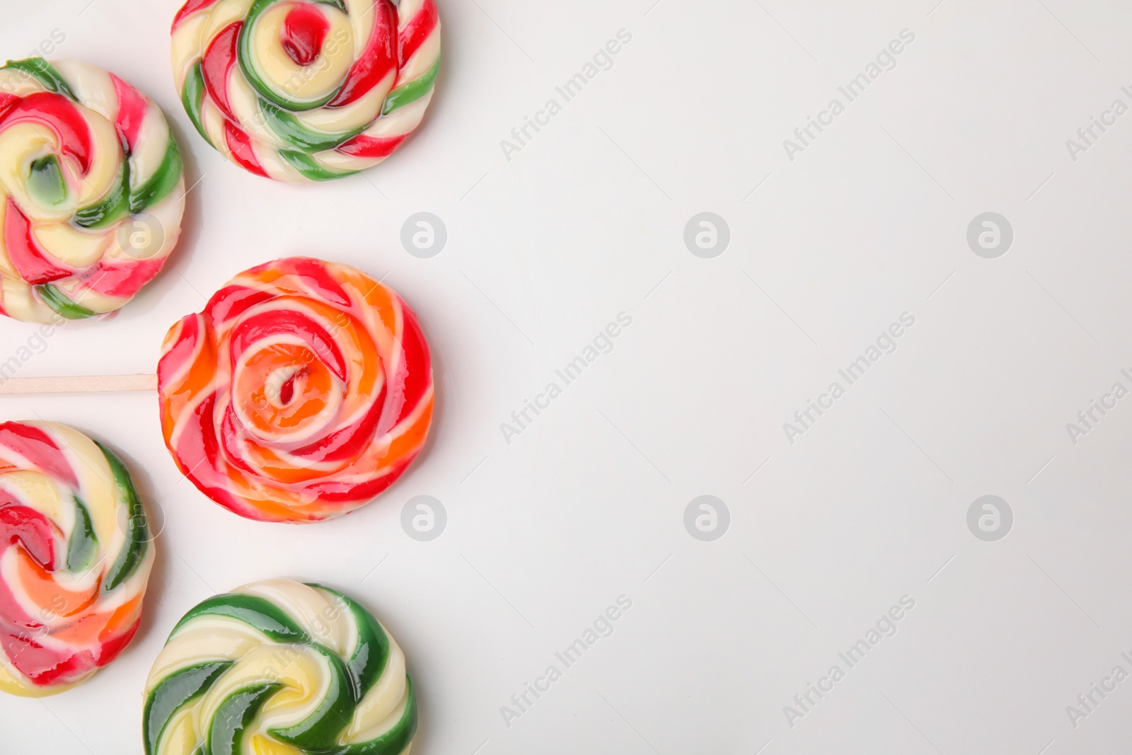 Photo of Many colorful lollipops on white background, flat lay. Space for text