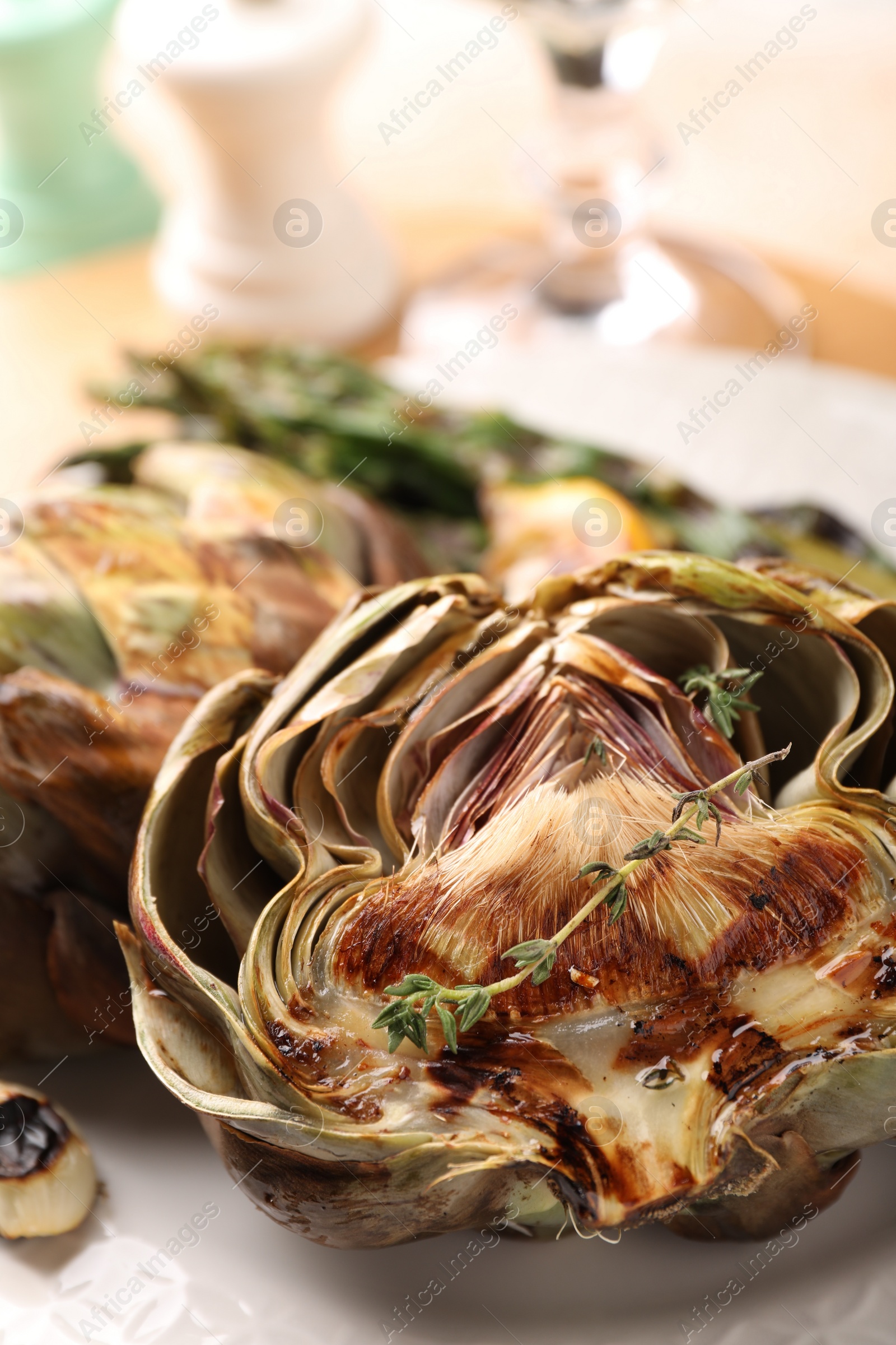 Photo of Tasty grilled artichokes on white plate, closeup