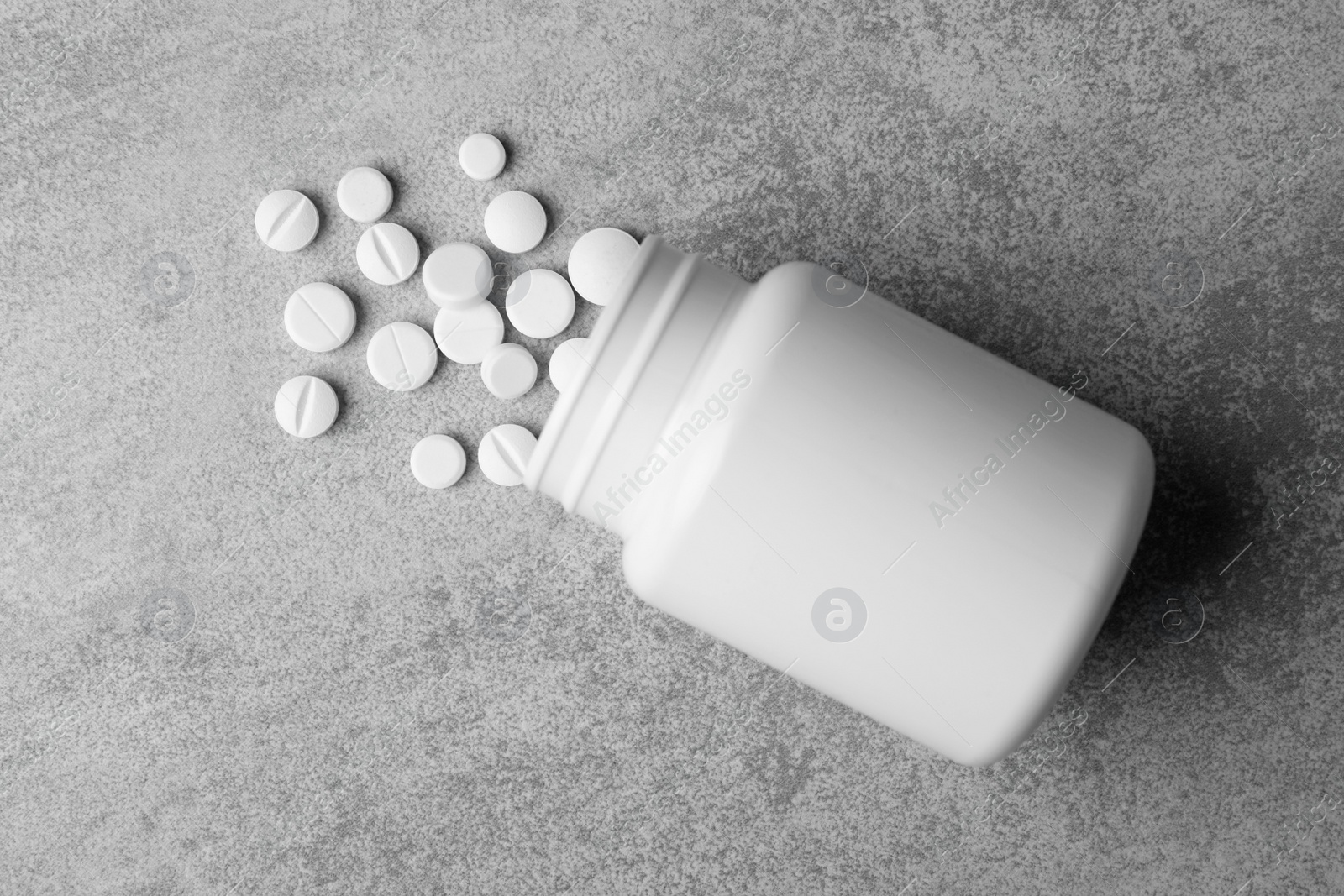 Photo of Bottle with different pills on grey background, flat lay