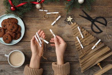 Photo of Woman making advent calendar at wooden table, top view