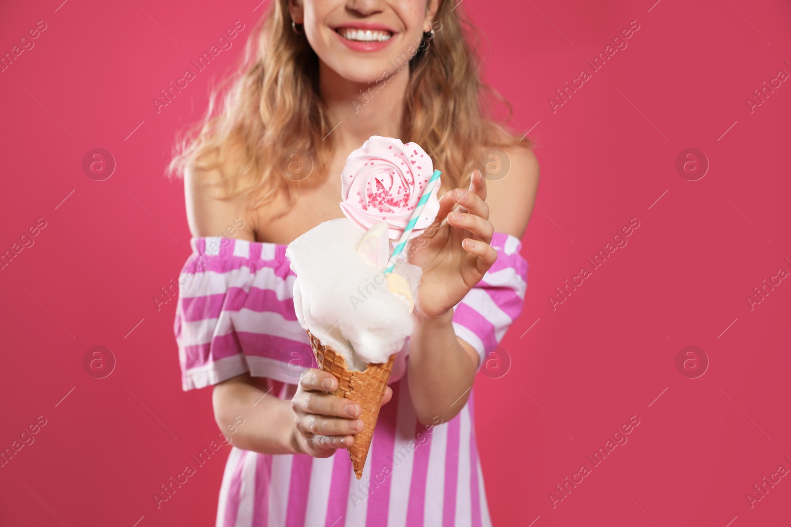 Photo of Young woman holding cotton candy dessert on pink background, closeup