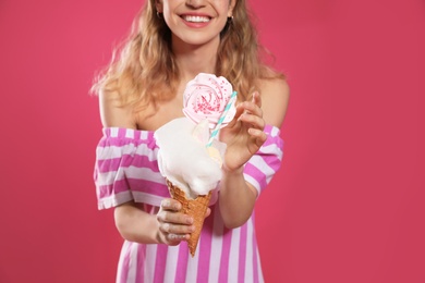 Young woman holding cotton candy dessert on pink background, closeup