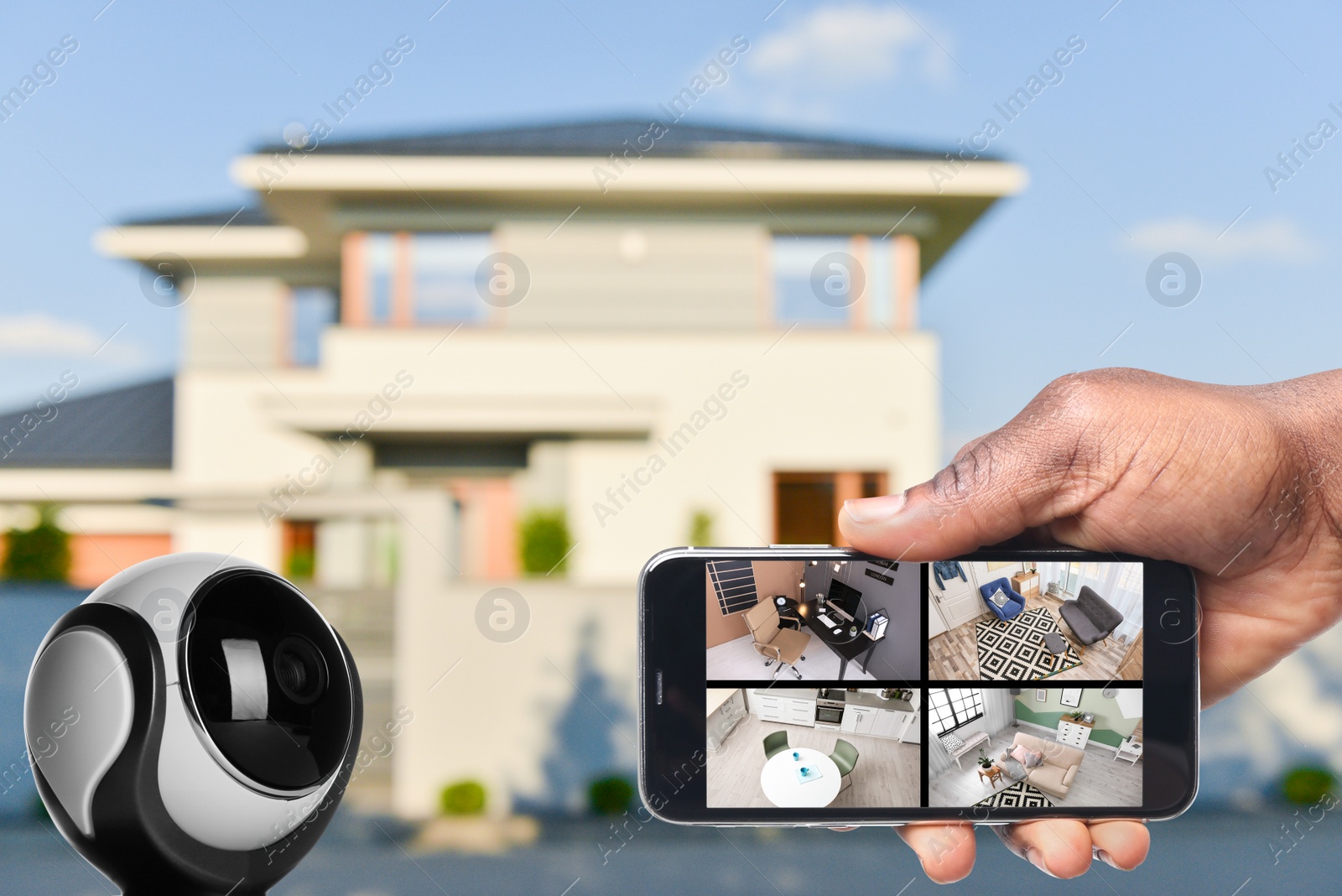 Image of Home security system. African American man monitoring CCTV cameras on smartphone near his house, closeup