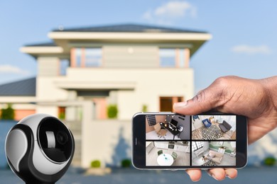 Image of Home security system. African American man monitoring CCTV cameras on smartphone near his house, closeup