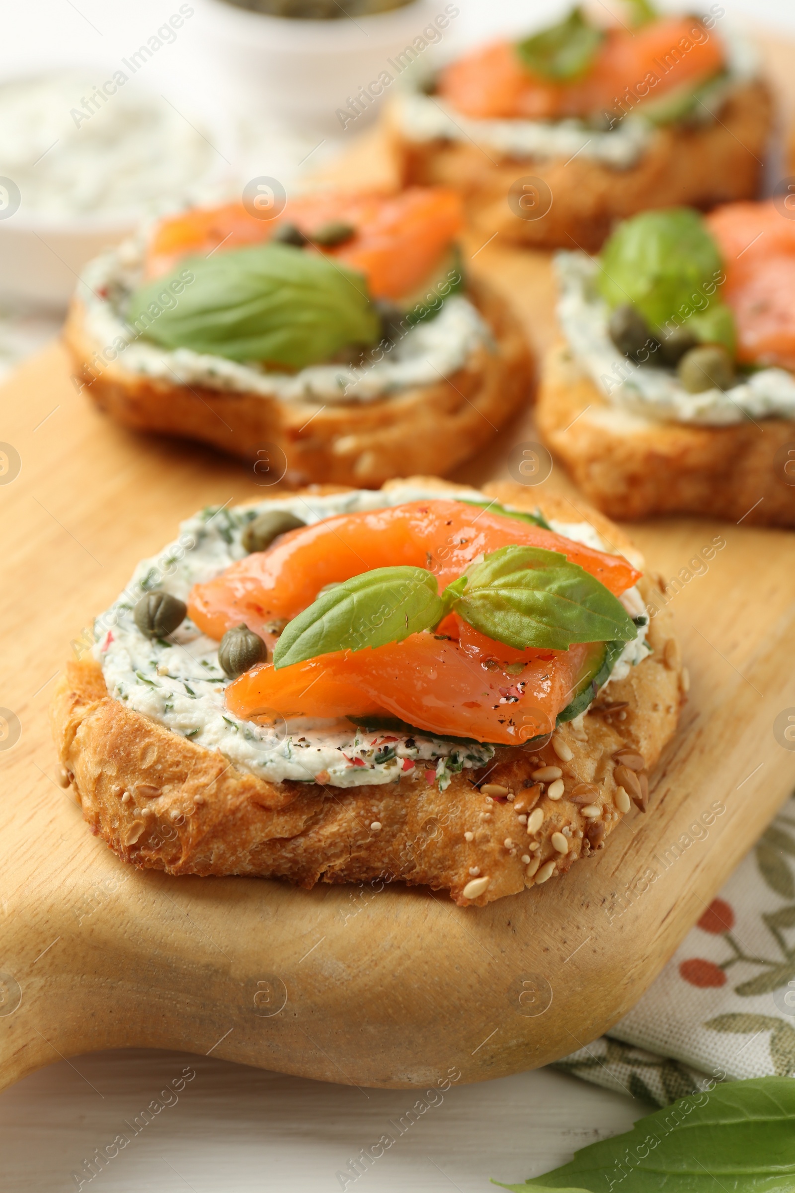 Photo of Tasty canapes with salmon, capers and sauce on white wooden table, closeup